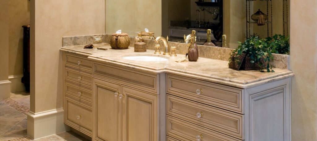 Elegant double sink bathroom vanity with cream cabinetry, marble countertop, and brass fixtures in a spa-like setting.