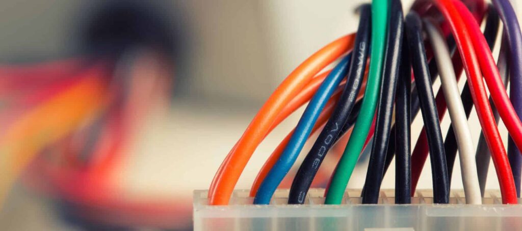 Bundle of colored electrical wires including orange, blue, black, green, white, and red cables arranged in a fan pattern.
